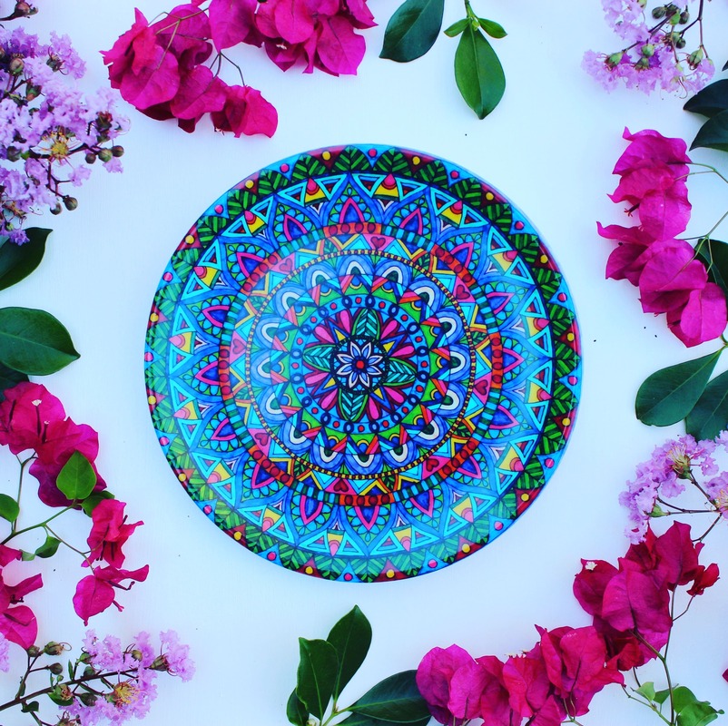 Beautiful and colourful mandala plates surrounded by pink and purple flowers