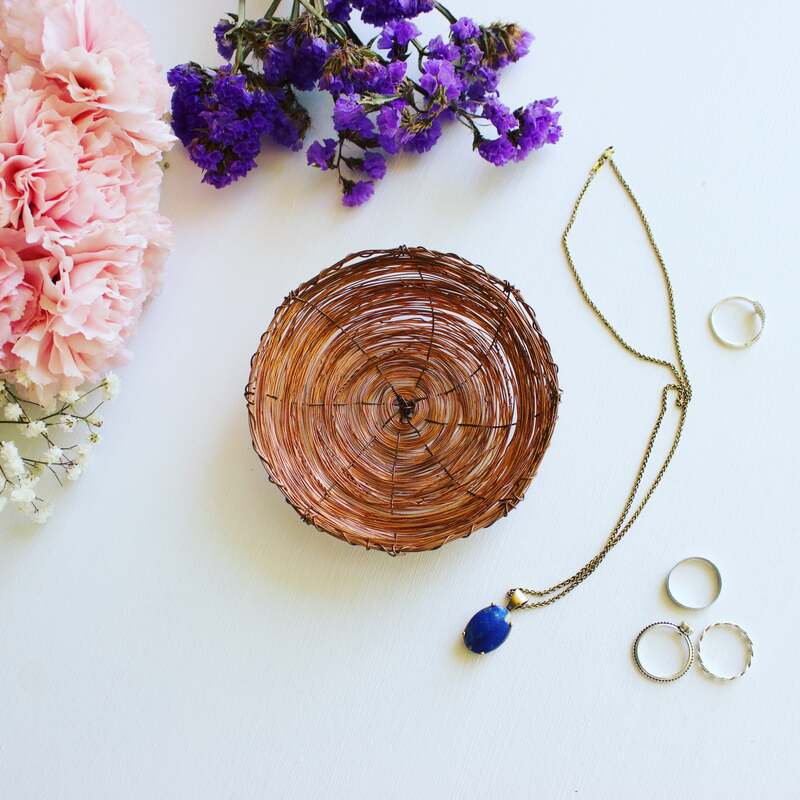 Copper jewellery dish styled with handcrafted jewellery and pink flowers