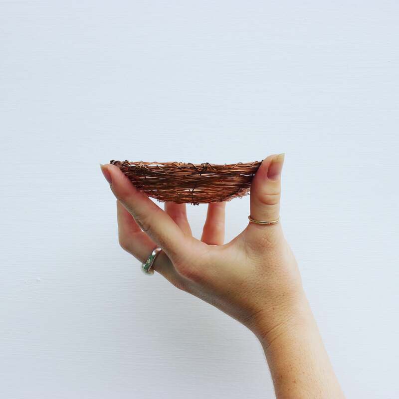 Hand with pearl rings holding a handcrafted copper jewellery dish