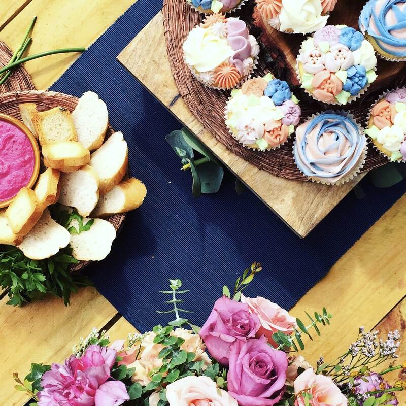 Beautiful tableware surrounded by colourful cupcakes and pretty flowers